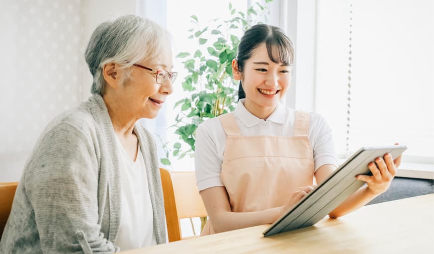 利用者にタブレットを使って説明を行う介護スタッフ