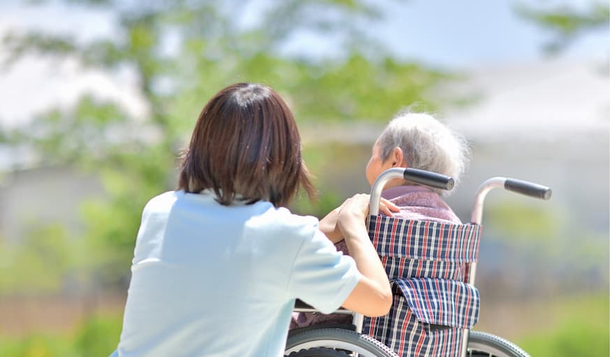 車いすに座る利用者に優しく寄り添う介護スタッフ